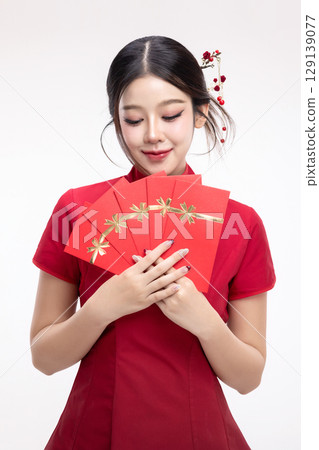 Portrait of joyful beauty Asian woman in red Cheongsam Chinese traditional dress celebrating with lucky red envelopes on Chinese New Year festival isolated on white background. Portrait of joyful beauty Asian woman in red Cheongsam Chinese traditional dress celebrating with lucky red envelopes on Chinese New Year festival isolated on white background. 129139077