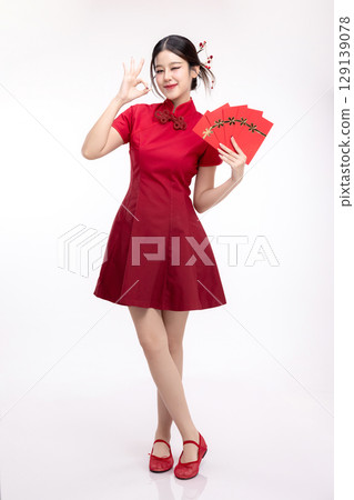 Portrait of joyful beauty Asian woman in red Cheongsam Chinese traditional dress celebrating with lucky red envelopes on Chinese New Year festival isolated on white background. Portrait of joyful beauty Asian woman in red Cheongsam Chinese traditional dress celebrating with lucky red envelopes on Chinese New Year festival isolated on white background. 129139078
