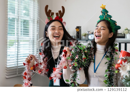 Festive Celebration with Friends Wearing Christmas Accessories and Laughing Together in a Bright, Joyful Holiday Atmosphere 129139112