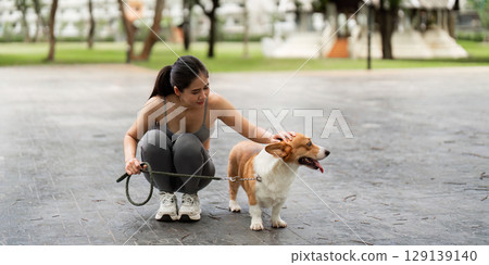 Pet Care. Young woman enjoying time with her corgi dog in a park 129139140