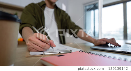 Working from Home. Creative Professional Taking Notes and Using Laptop 129139142