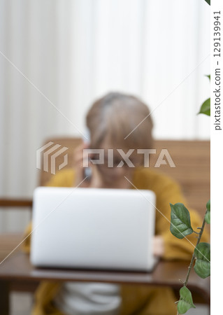 老年人在客廳看著電腦,擔心老年婦女的生活方式和失智症 老年人在客廳看著電腦,擔心老年婦女的生活方式和失智症 129139941