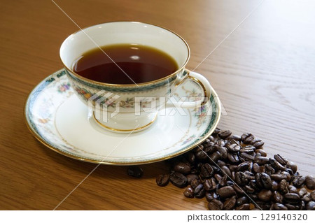 Hot black coffee and roasted beans served in a beautiful cup 129140320
