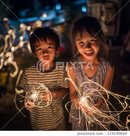 溫暖的夏日場景,孩子們的笑容和手持的煙火 溫暖的夏日場景,孩子們的笑容和手持的煙火 129140684