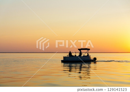Pontoon Boat on Calm Water at Sunset A Serene Evening Cruise Experience on the Lake 129141523