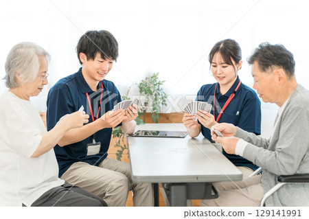 集體住宅或養老院裡的老年人打牌,以及男性和女性護理人員 集體住宅或養老院裡的老年人打牌,以及男性和女性護理人員 129141991