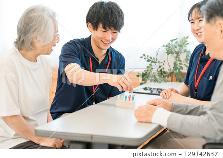 老年人和職業治療師在復健期間使用圓柱釘進行手部和手指功能訓練 129142637