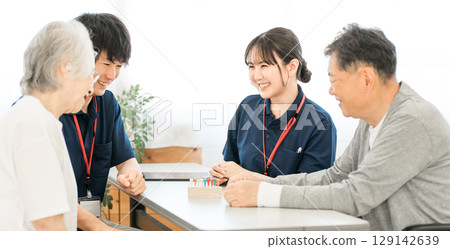Seniors and occupational therapists using cylinder pegs for hand and finger function training during rehabilitation 129142639