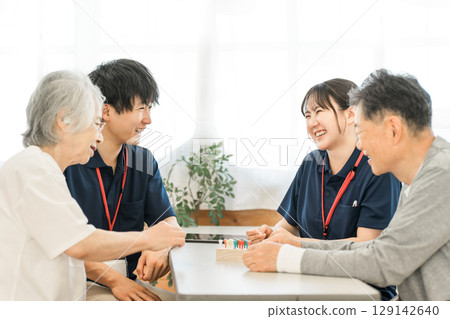 Seniors and occupational therapists using cylinder pegs for hand and finger function training during rehabilitation 129142640
