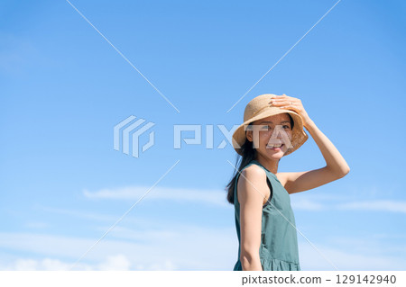 藍天下戴草帽的年輕女子 129142940