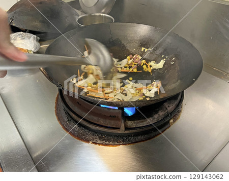 Shot of chef mixing ingredients for fried rice in the kitchen Shot of chef mixing ingredients for fried rice in the kitchen 129143062