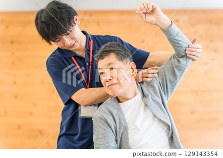 A male physiotherapist providing physical therapy to a senior manA male physiotherapist providing physical therapy to a senior man A male physiotherapist providing physical therapy to a senior manA male physiotherapist providing physical therapy to a senior man 129143354