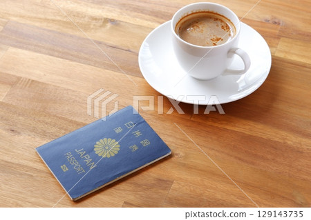 一個人一邊喝咖啡一邊準備護照（5年期海軍藍普通護照）併計劃出國旅行的圖片 129143735