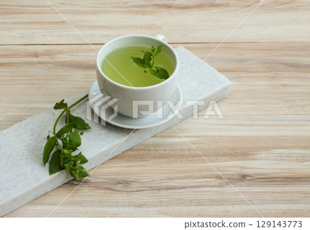 A cup of fresh tea from Chickweed, lat. Stellaria media on white marble. A cup of fresh tea from Chickweed, lat. Stellaria media on white marble. 129143773