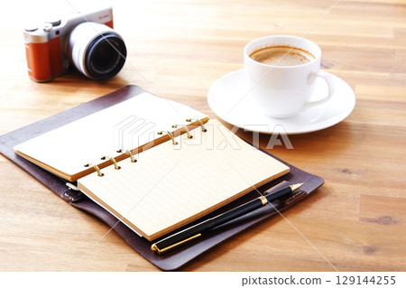 An image of someone writing in a diary while drinking a cafe latte, a coffee with plenty of milk. An image of someone writing in a diary while drinking a cafe latte, a coffee with plenty of milk. 129144255
