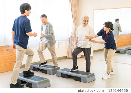Senior men and women training at a day service/personal gym and a young male instructor 129144466
