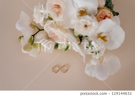 Wedding Rings And White Flowers On Beige Background Wedding Rings And White Flowers On Beige Background 129144632