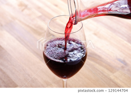 慢慢地將紅酒倒入酒杯中 慢慢地將紅酒倒入酒杯中 129144704