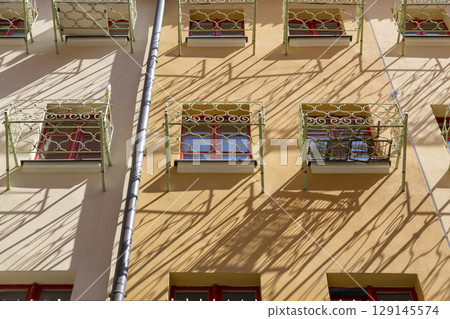 Facade of a residential building with small balconies in front of the window 129145574