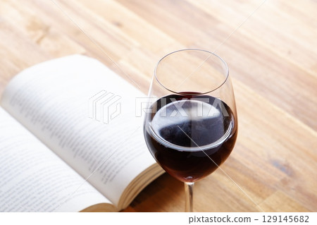 A glass of wine and a book - Enjoying a book while drinking red wine A glass of wine and a book - Enjoying a book while drinking red wine 129145682