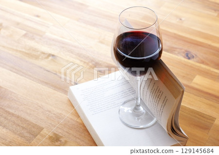 A glass of wine and a book - Enjoying a book while drinking red wine 129145684