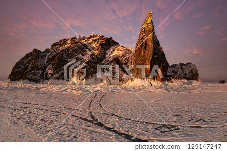A breathtaking view of snow-covered mountains in lake baikal, Russia, illuminated by the soft glow of sunrise. The vast expanse of icy terrain creates a serene winter atmosphere. 129147247