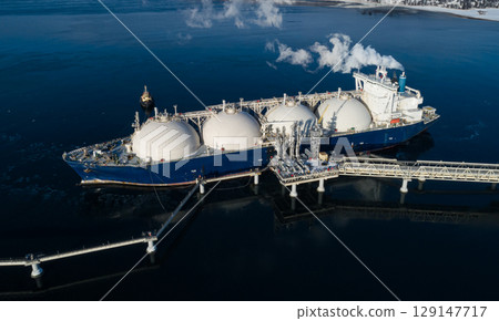 Aerial of Liquified Natural Gas LNG carrier moored to a small gas terminal at night. Fuel crisis. Sanctions. Aerial of Liquified Natural Gas LNG carrier moored to a small gas terminal at night. Fuel crisis. Sanctions. 129147717