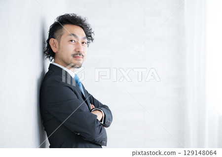 A bearded businessman with his arms crossed, looking at the camera. A smiling and positive image. 129148064