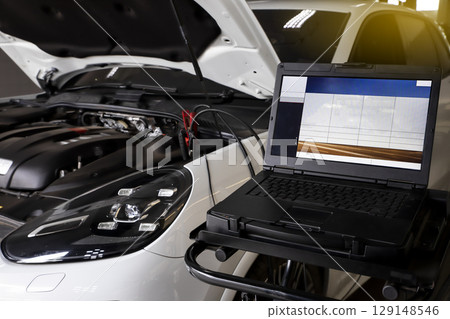 Mechanic use laptop near car engine. Modern car diagnostic program on screen. Car service concept. Mechanic use laptop near car engine. Modern car diagnostic program on screen. Car service concept. 129148546