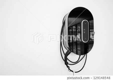 Electric car charging on parking lot with electric car charging station on city street. Close up of power supply plugged into an electric car being charged. 129148548