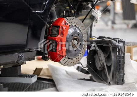 Front disc brake system on race car in process of damaged tyre replacement. The rim is removed showing the front rotor and caliper. Front disc brake system on race car in process of damaged tyre replacement. The rim is removed showing the front rotor and caliper. 129148549