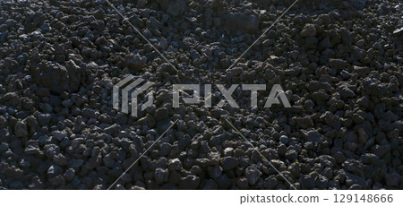 Black volcanic desert land with basalt lava formations and stones, a dark soil of the volcano. 129148666