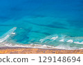 Blue ocean with waves and a sandy beach, top view. 129148694