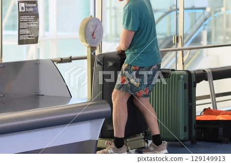 旅客在機場辦理登機手續前對行李進行稱重 129149913
