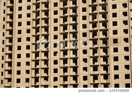 An Abstract Concrete Wall featuring Repetitive Patterns of Windows in its Design and Structure 129150069