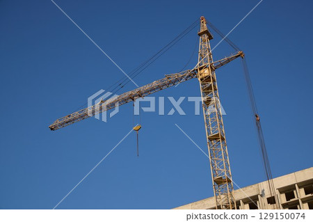 A tall crane under a clear blue sky symbolizes progress in construction and urban growth 129150074