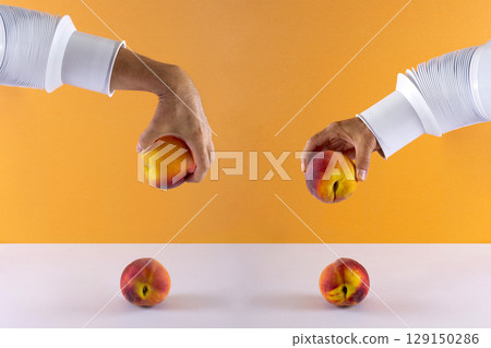 Two male hands with a peach over the table on a colored background 129150286