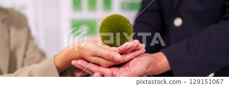 Business professionals collaborate hands holding green sphere fostering sustainable development environmental protection and economic growth initiatives Business professionals collaborate hands holding green sphere fostering sustainable development environmental protection and economic growth initiatives 129151067