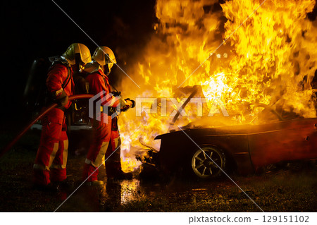 Firefighter training, fireman using water and extinguisher to fighting with fire flame in an emergency situation., under danger situation all firemen wearing fire fighter suit for safety. 129151102