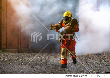 Firefighter rescue, Fireman walking out from burning building and hold save a child in his arms from fire incident. 129151150