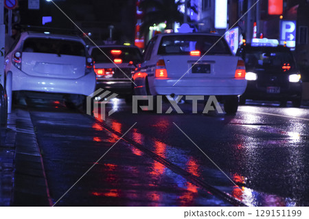 濕滑路面上倒映的霓虹燈和汽車 濕滑路面上倒映的霓虹燈和汽車 129151199