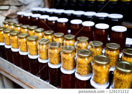 Assorted honey and pollen jars displayed on wooden shelf in rustic setting Assorted honey and pollen jars displayed on wooden shelf in rustic setting 129151212