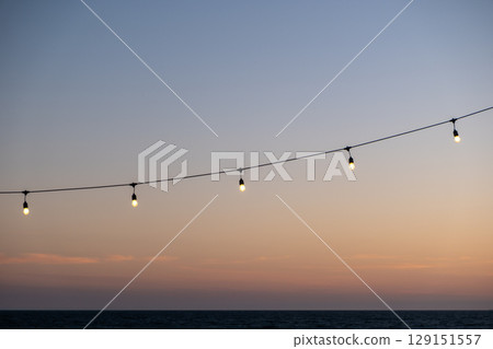 Light bulb, hanging string light with sunset beach view in the background Light bulb, hanging string light with sunset beach view in the background 129151557