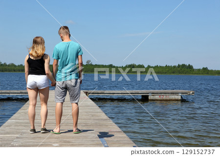 A Couple Experiencing the Joy of a Sunny Day at the Beautiful Lakeside Pier Together A Couple Experiencing the Joy of a Sunny Day at the Beautiful Lakeside Pier Together 129152737