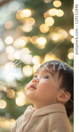 asian baby against blurred Christmas tree, New Year, banner asian baby against blurred Christmas tree, New Year, banner 129152846