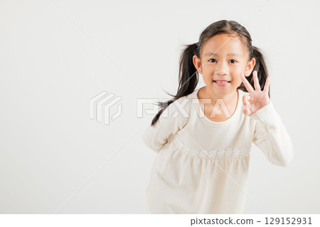 Exuberant young kid girl showcases the OK sign with an optimistic smile, conveying agreement and positivity isolated on a white background, ideal for your text customization. kindergarten child smile Exuberant young kid girl showcases the OK sign with an optimistic smile, conveying agreement and positivity isolated on a white background, ideal for your text customization. kindergarten child smile 129152931
