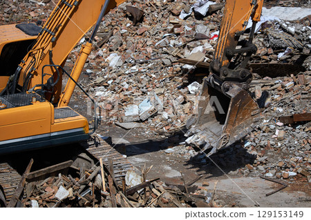 Excavator stands on rubble of house. Dismantling process, demolition of old building, destruction of dilapidated housing Excavator stands on rubble of house. Dismantling process, demolition of old building, destruction of dilapidated housing 129153149
