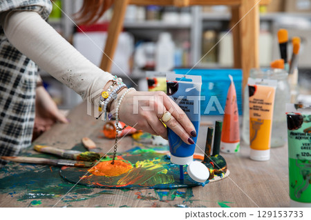 Engaging in a Creative Painting Process Using Vibrant Colors and Various Art Supplies 129153733
