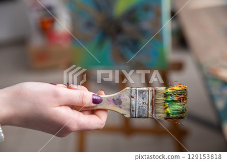 An Artists Paintbrush Surrounded by a Vibrant Array of Colorful Paints in a Creative Studio An Artists Paintbrush Surrounded by a Vibrant Array of Colorful Paints in a Creative Studio 129153818