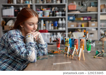 A young artist reflects in their studio, surrounded by colorful paints and honing their skills A young artist reflects in their studio, surrounded by colorful paints and honing their skills 129153845